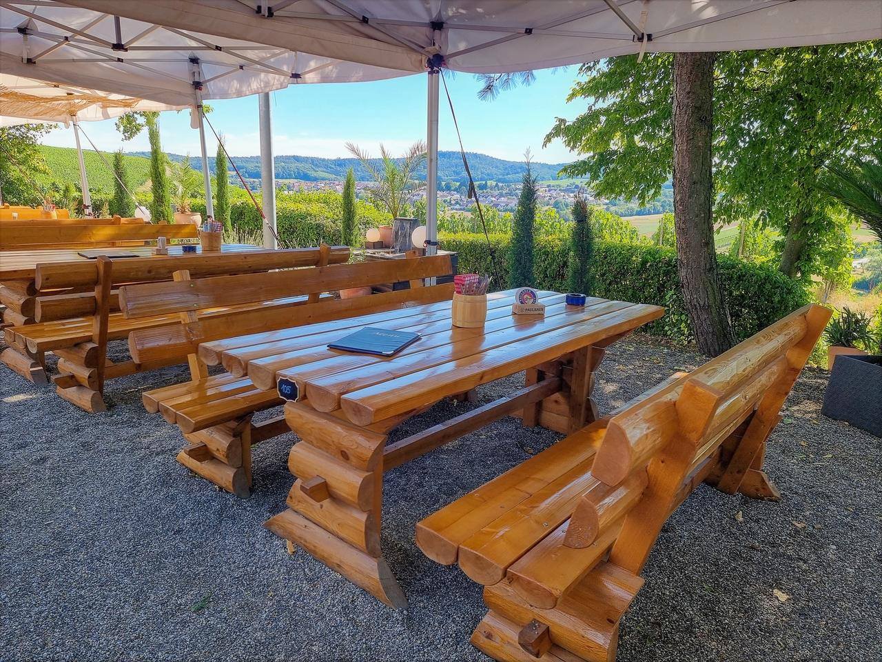 Massive Holzbänke im Biergarten mit Blick über das Sulmtal