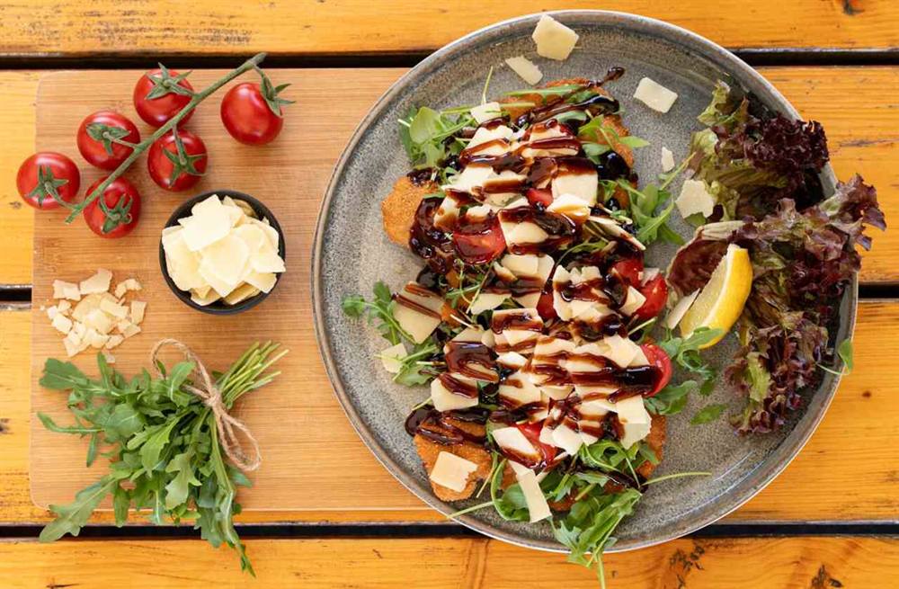 Schnitzel mit Rucola, Kirschtomaten, Parmesansplittern und Balsamicocreme